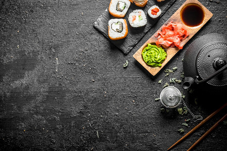 美味的日本寿司卷绿色茶和酱汁黑生锈背景图片