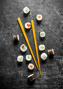 寿司卷和木棍子深黑的生锈背景背景图片