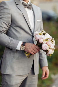时尚的新郎拿着娘花束婚礼在人手里图片
