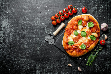 土制披萨和西红柿在树枝迷迭香上在黑暗的生锈背景上土制披萨和西红柿在树枝迷迭香上图片