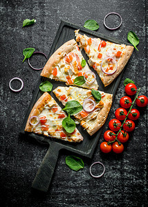 一片披萨和西红柿在树枝上菠菜黑暗的生锈背景上一些披萨和西红柿在树枝菠菜上图片