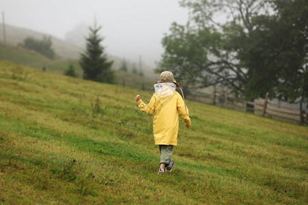 穿黄色雨衣的女孩在雾山中行走背景图片