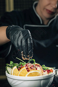 餐厅的女厨师配着芝麻的沙拉装饰背景图片