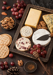 在木本底的古董盒葡萄中选择各种奶酪蓝宝石红色李斯特白奶酪和加饼干蜂蜜的坚果图片