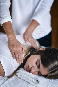 女抗逆转录治疗师的垂直形象肩上握着病人的膀和转移能量平的少女闭着眼睛躺减轻压力和放松的替代治疗概念图片