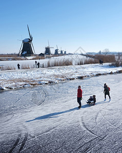 12februay201家庭在冰上滑阳光明媚的冬季日子里与许多风车一起图片