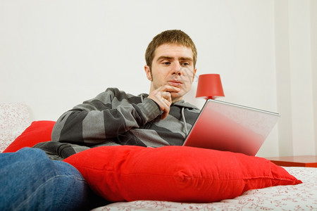 在床上操作计算机的青年男图片