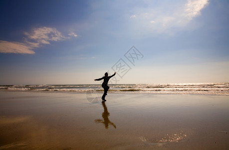 年轻妇女在湿沙滩上奔跑图片