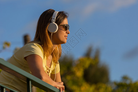 放音乐的女孩美丽的临时女在日落享受音乐用耳机在户外放背景