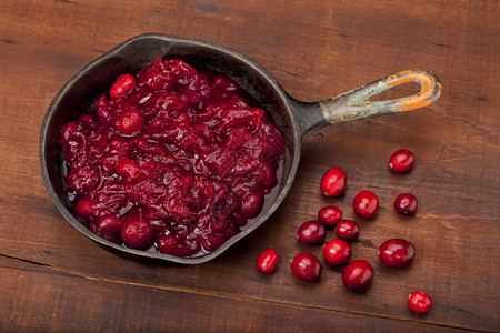 在一个小铁锅和些新鲜的莓子上用一个小铁锅和些新鲜的果子用一个旧的刮过木桌顶图片