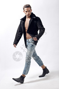 身穿冬季夹克和白色背景行走的年轻男模特图片