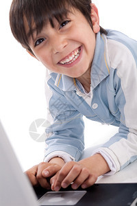 带着笔记本电脑在白色背景上微笑的可爱caucasian男孩的肖像图片