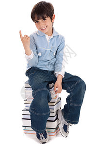 年轻男孩坐在白背景的书塔上图片