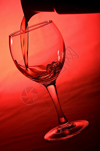 红底倒入玻璃中的葡萄酒图片