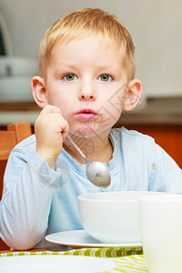 金发男孩子在厨房桌边吃早饭图片