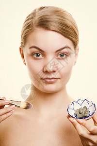 照顾皮肤用刷子在脸上戴粘土面具的年轻女照顾干燥的情谊女孩施虐和美容治疗背景图片