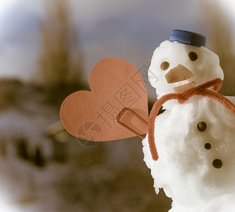 圣诞小雪人穿着蓝螺丝顶的色雪人帽子红围巾和心爱的短片符号牙签在户外冬季节特定情人39日蓝天空背景塞皮亚语调图片