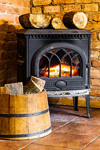 在家冬天用橙色火焰和木柴关闭壁炉在桶内加热图片