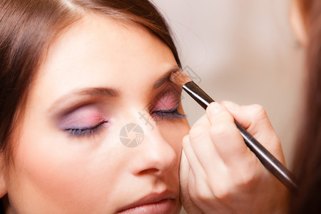 女美貌化妆艺术家的造型师在年轻女眉毛上用刷子化妆图片