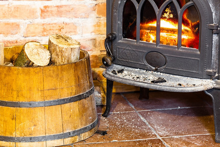 在家冬天用橙色火焰和木柴关闭壁炉在桶内加热图片