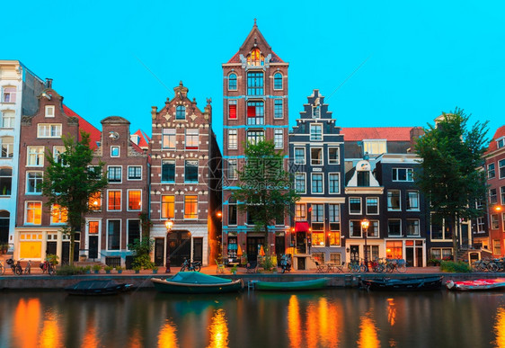 荷兰阿姆斯特丹运河和典型房屋船只和自行车的夜间城市景色图片