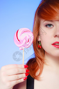 半张女脸感年轻女人拿着糖果红头发女孩在紫罗兰吃甜棒糖工作室拍甜图片
