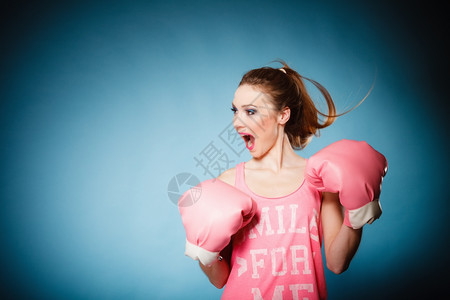 穿着粉红色大手套玩运动拳击头发演播室拍蓝色背景图片