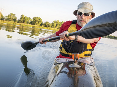 高年男在科罗拉多州林斯堡的平静湖上划着翅膀桨一条快速赛跑的海上皮艇图片