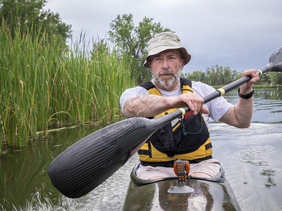 在科罗拉多州湖边的一条狭小快赛独木舟中训练高级男护父图片