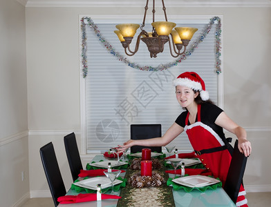 年轻少女穿着圣诞老人服装为节假日安排餐厅桌图片