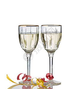 盛满白葡萄酒的优美杯与白色背景隔绝与反光和派对的丝带相隔绝图片