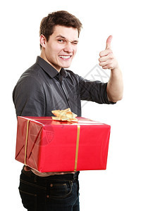 英俊的年轻人送红礼物盒带金丝并举起拇指成功手牌图片