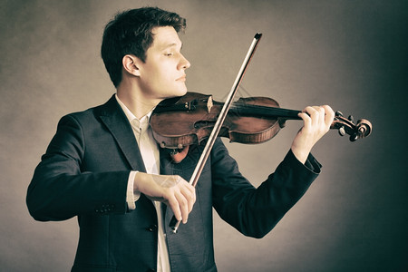年轻优雅的小提琴家手在棕色和古典音乐上拉小提琴背景图片