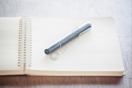 空白螺旋日记本上放着一支笔背景图片