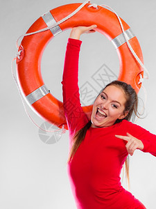 年轻女在值勤时微笑的女救生员持有浮标救生设备在灰色上玩得开心图片