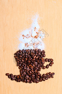 卡布奇诺时间烤咖啡豆以木制表面背景上含肉桂白霜的杯子和碟形式图片