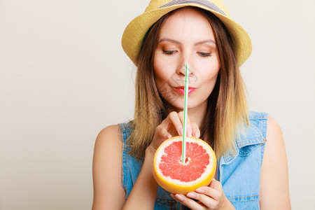 暑假快乐的有趣女游客戴着葡萄果仁柑橘的帽子喝着灰色水果上的汁图片