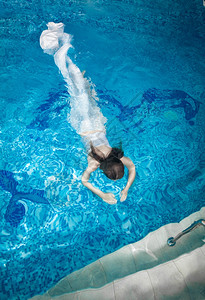 穿着长白裙子的感女人在游泳池水下潜图片