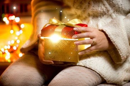 女青年打开礼物盒亮着灯光的特写照片图片