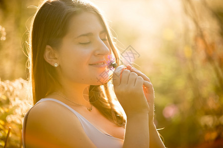 可爱女人的美丽肖像在阳光明媚的日子里田闻着花香的可爱女人美丽肖像图片