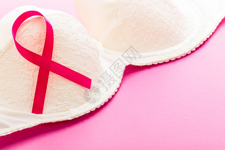 保健医药和乳腺癌认识概念粉红背景女胸罩上的粉色丝带缝合图片