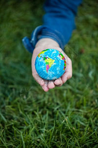 近距离拍摄女孩在草原上手握着小地球的近镜头图片