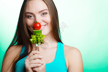 美食和减肥概念有趣的女孩健身人拿着叉子和新鲜混合蔬菜绿色蓝背景图片