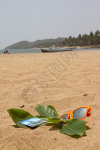 印度果阿橙色太阳眼镜和纸牌沙滩上的印度果子图片