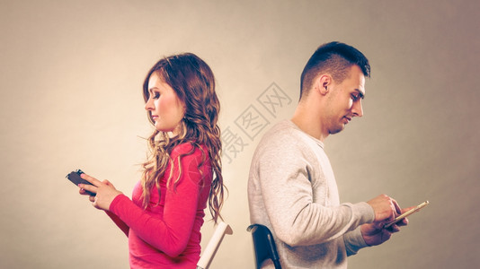 使用移动电话的夫妇不相互交谈沮丧的男女使用新技术逐渐分裂Instagram过滤使用移动电话的夫妇不说冲突图片