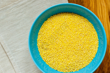 饮食保健概念蓝碗里的小米放在木制桌上健康食物高蛋白含量图片