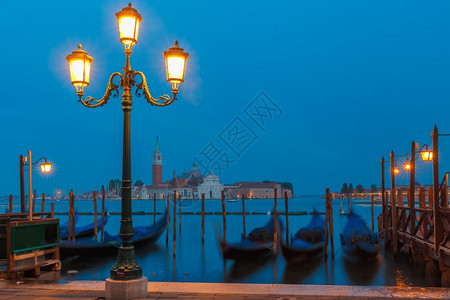 Gondolas由圣马克广场和乔治马吉奥雷教堂在意大利威尼斯环礁湖天明时的背面挂起图片
