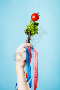 饮食和减肥概念糖尿病女手与素食和彩色测量磁带蓝背景图片