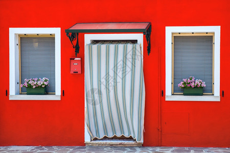 意大利威尼斯著名的布拉诺岛近身装饰着花朵窗户和百叶的丰富多彩房屋图片