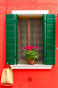 在著名的意大利威尼斯岛布拉诺的红墙上有绿色百叶窗和鲜花的图片口图片